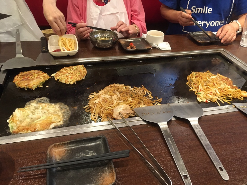大きな鉄板でお好み焼きや焼きそばを焼いている様子
