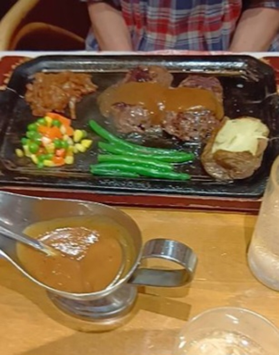 特製ソースがたっぷりかかったハンバーグと食事を楽しむ様子